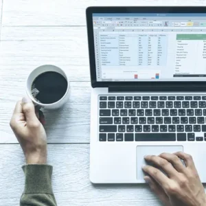 a man with a coffee in his cand and working with laptop