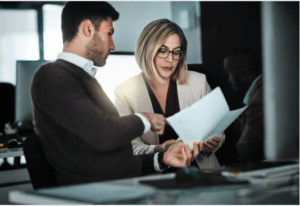 Two business professionals reviewing a document together in a modern office setting.
